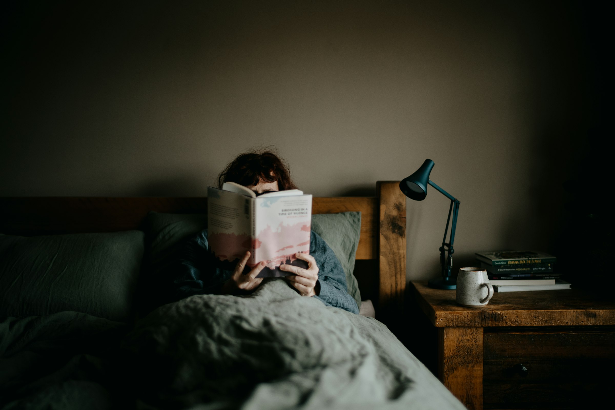 Une personne lit au lit, à la lumière d’une lampe de chevet
